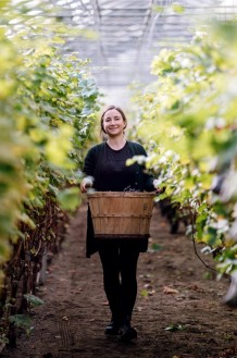 Julie Zyromski, owner of the winery, walking in the vines with grapes in her hand